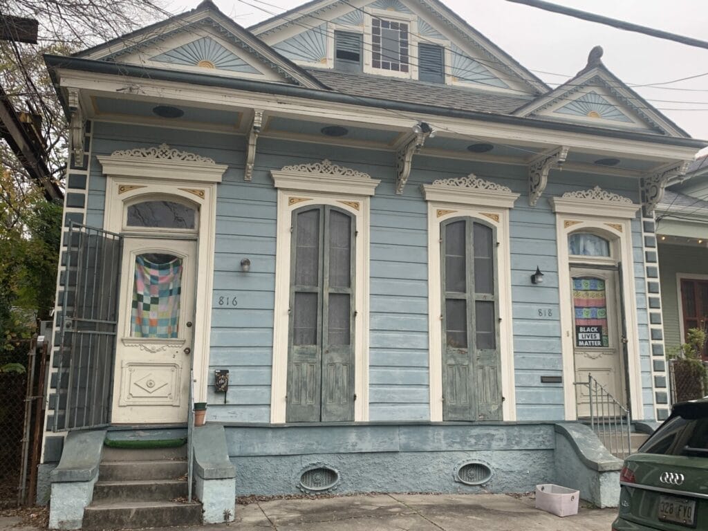 Vibrant and colorful homes lining the streets of New Orleans, showcasing a kaleidoscope of hues and tones. A calming light blue with ivory trim and door.