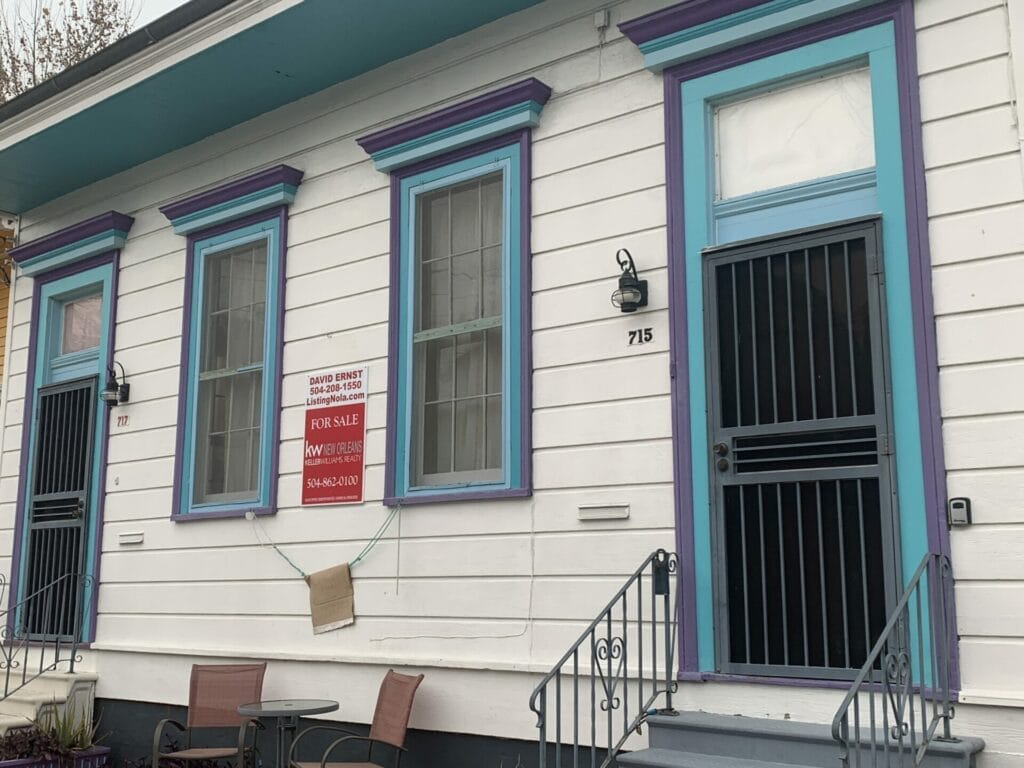 Vibrant and colorful homes lining the streets of New Orleans, showcasing a kaleidoscope of hues and tones. Cream house with blue trim house.