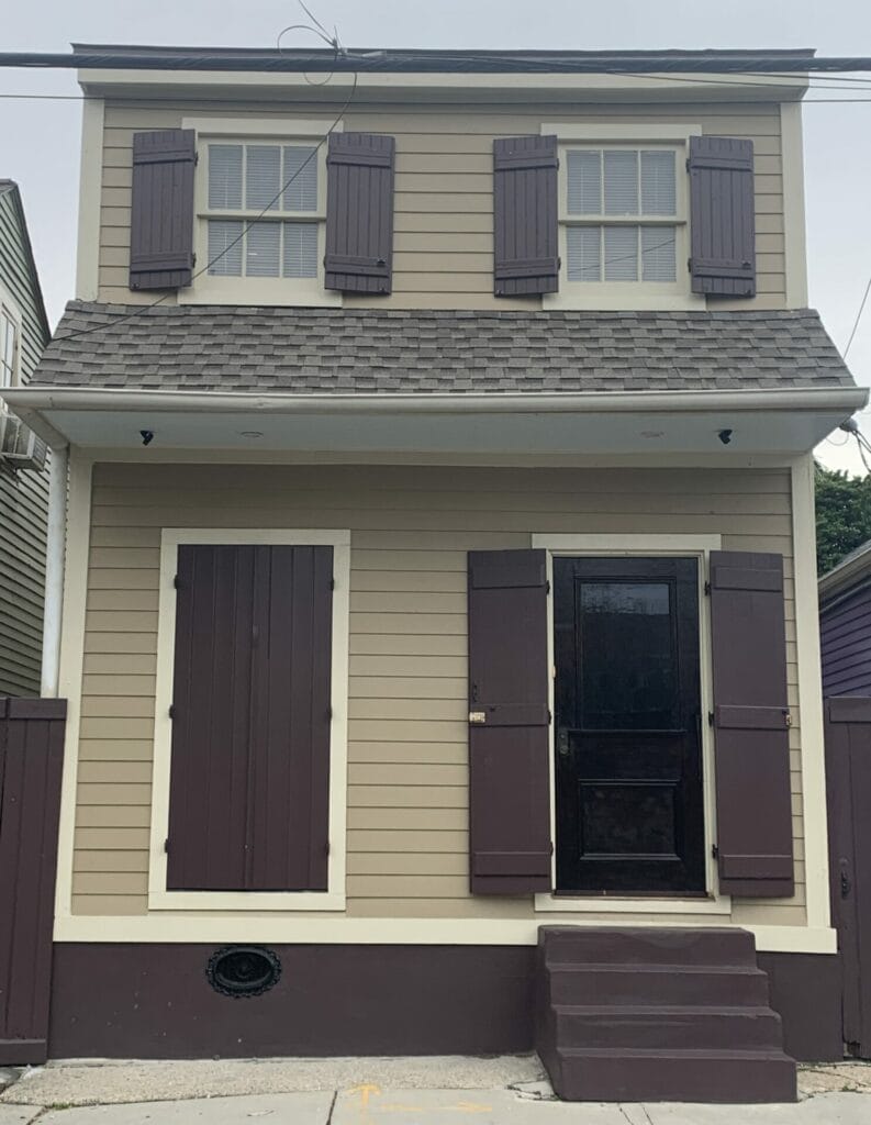 Vibrant and colorful homes lining the streets of New Orleans, showcasing a kaleidoscope of hues and tones. Brown door and shutters with a lighter wall.