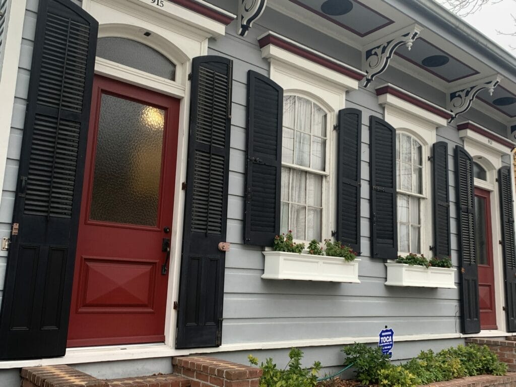 Vibrant and colorful homes lining the streets of New Orleans, showcasing a kaleidoscope of hues and tones. Grey house with red door is elegant.