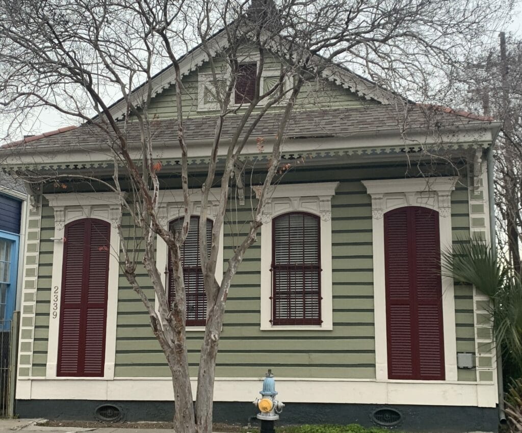 Vibrant and colorful homes lining the streets of New Orleans, showcasing a kaleidoscope of hues and tones. green with red doors house.