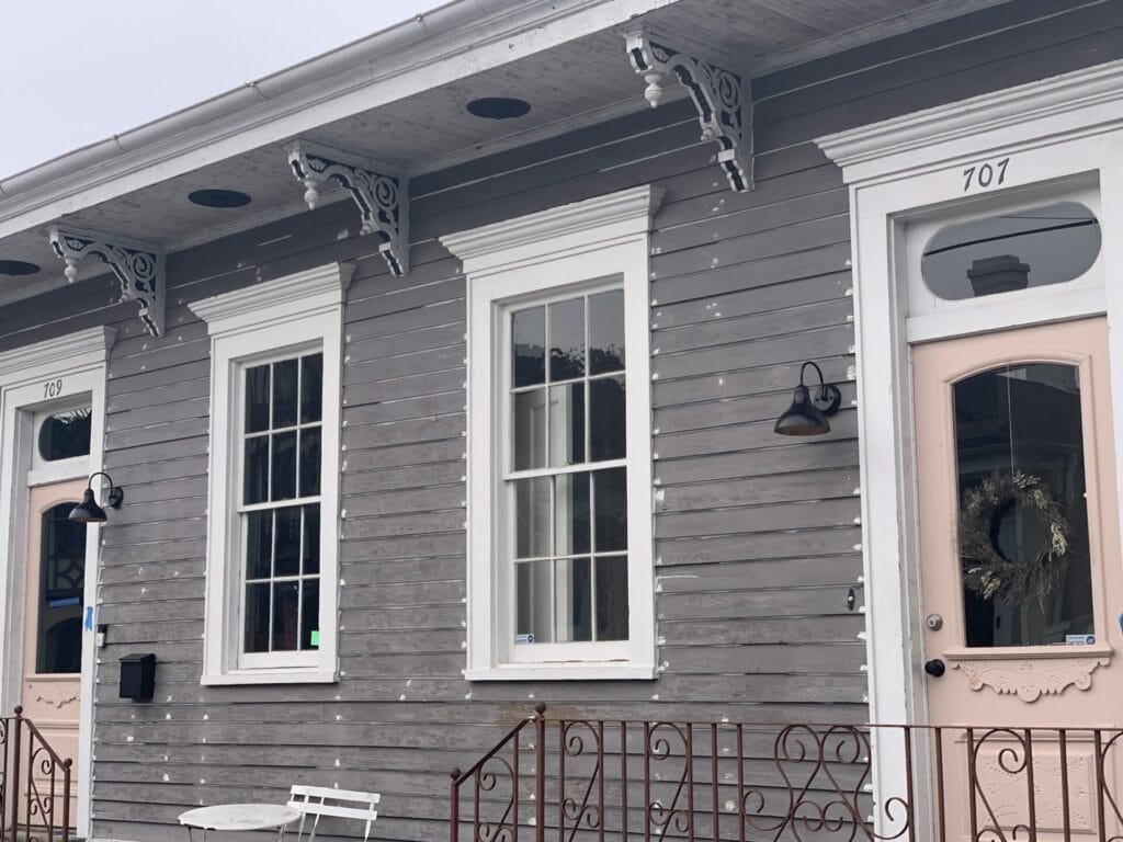 Vibrant and colorful homes lining the streets of New Orleans, showcasing a kaleidoscope of hues and tones. Grey and brown with white trim and pink door is very modern in color.