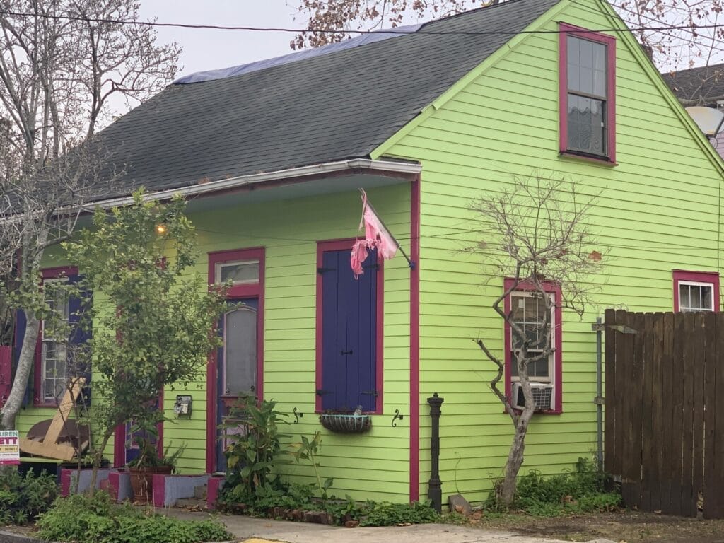 Vibrant and colorful homes lining the streets of New Orleans, showcasing a kaleidoscope of hues and tones. Bright green with red trim house.
