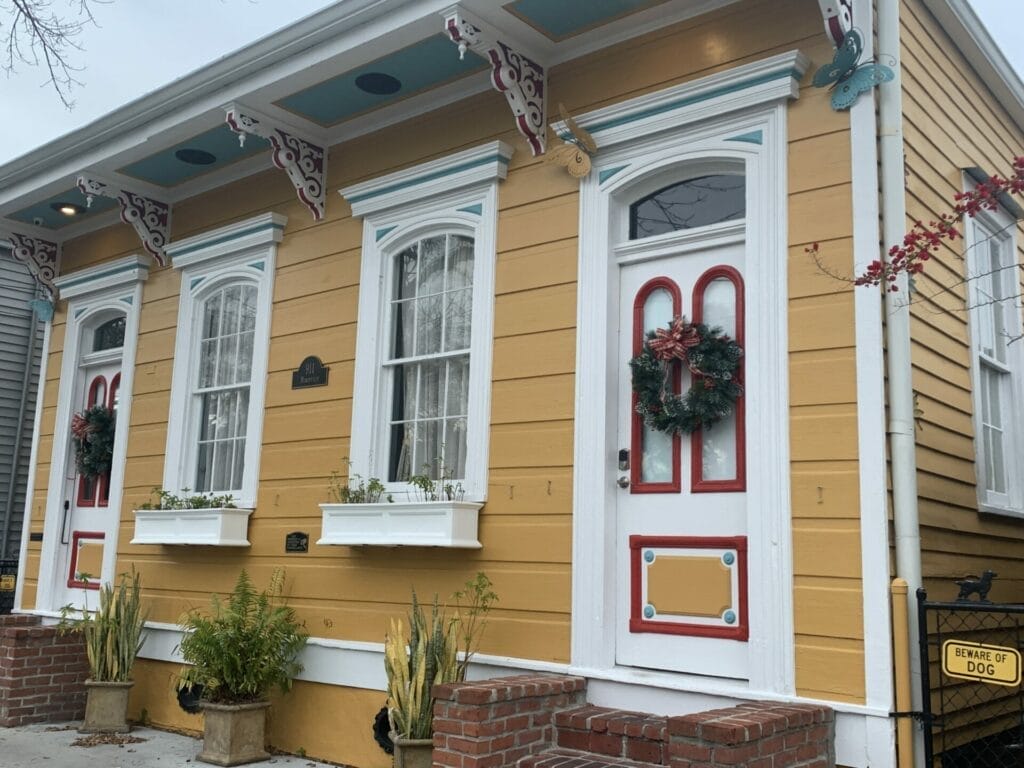 Vibrant and colorful homes lining the streets of New Orleans, showcasing a kaleidoscope of hues and tones. Orange with white door house.