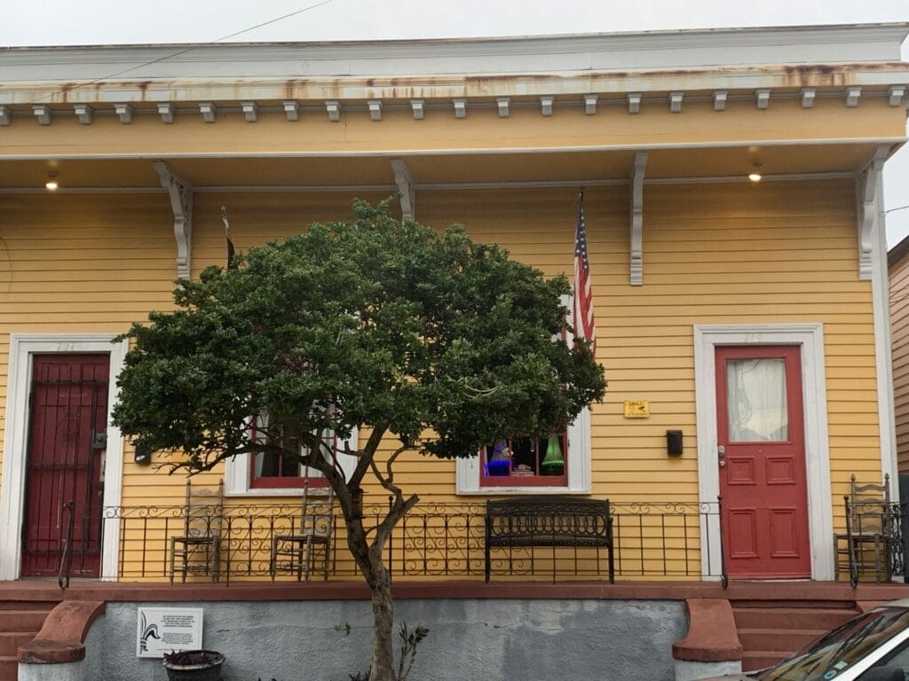 Vibrant and colorful homes lining the streets of New Orleans, showcasing a kaleidoscope of hues and tones. Peach house with red door.