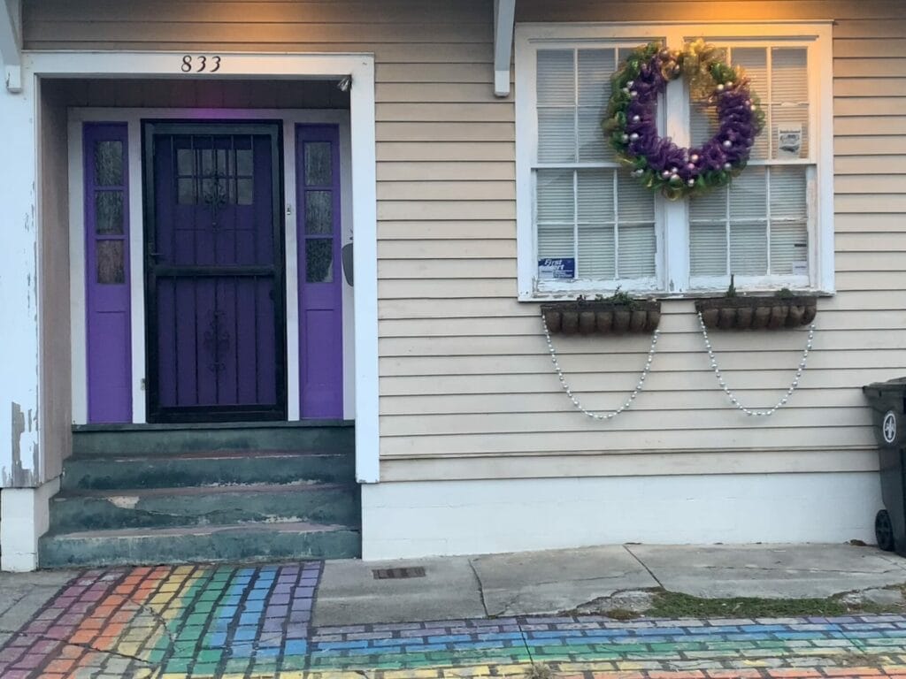 Vibrant and colorful homes lining the streets of New Orleans, showcasing a kaleidoscope of hues and tones. Tan with dark doors house.