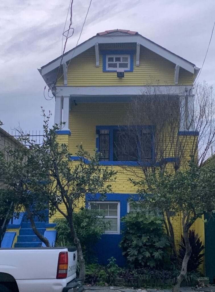 Vibrant and colorful homes lining the streets of New Orleans, showcasing a kaleidoscope of hues and tones. Sunny yellow narrow home.