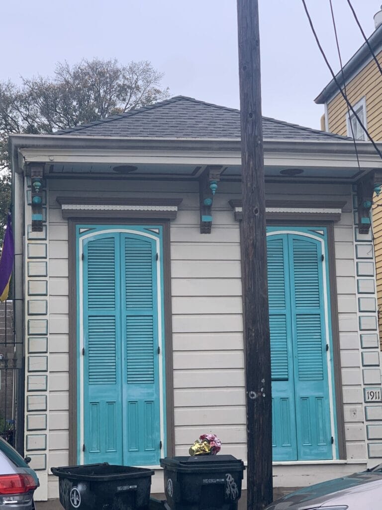 Vibrant and colorful homes lining the streets of New Orleans, showcasing a kaleidoscope of hues and tones. Brown with teal high ceiling shutters.