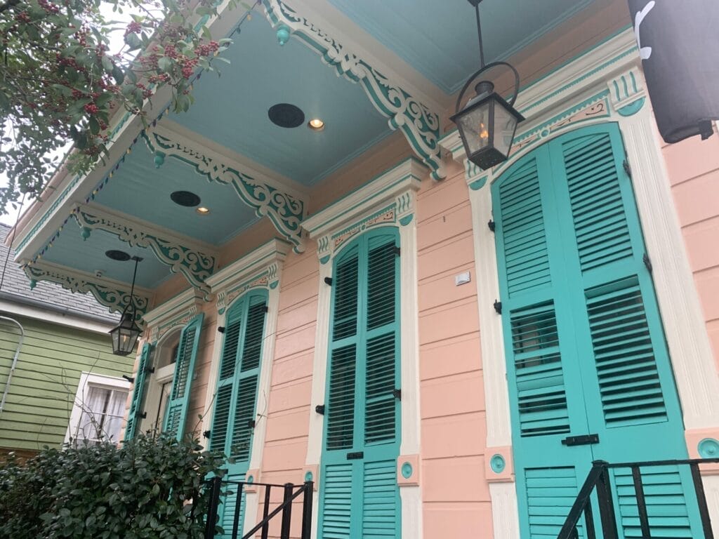 Vibrant and colorful homes lining the streets of New Orleans, showcasing a kaleidoscope of hues and tones. Soft peach with teal shutters home.