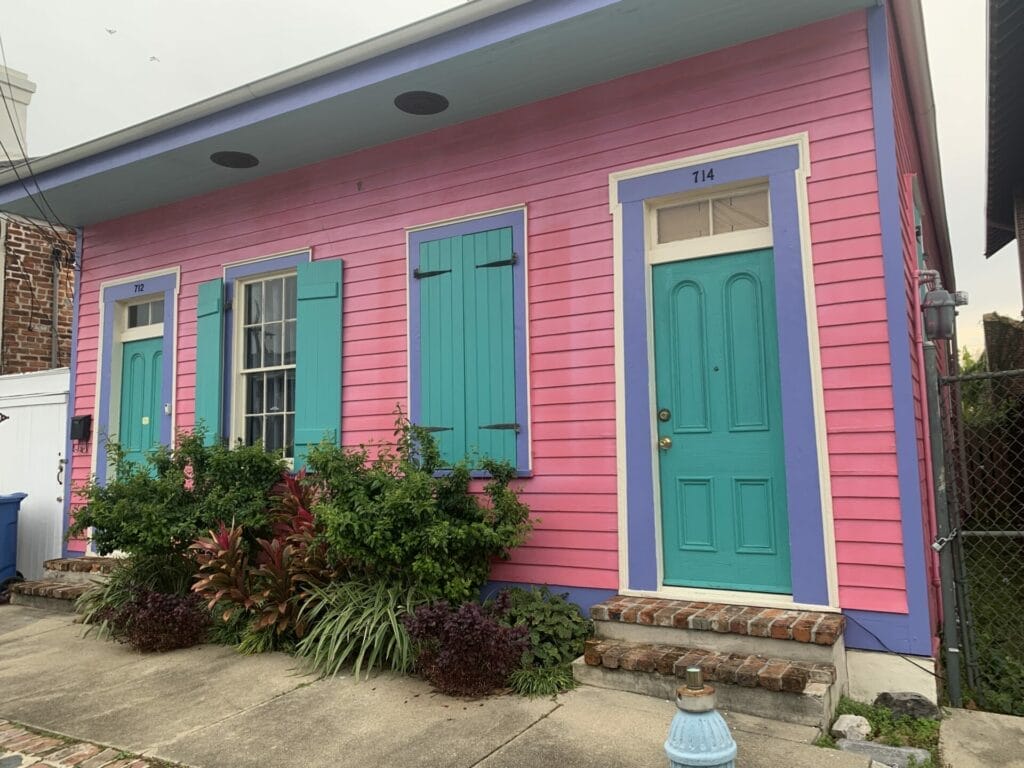 Vibrant and colorful homes lining the streets of New Orleans, showcasing a kaleidoscope of hues and tones. Colorful combination of teal, pink, purple and cream house.