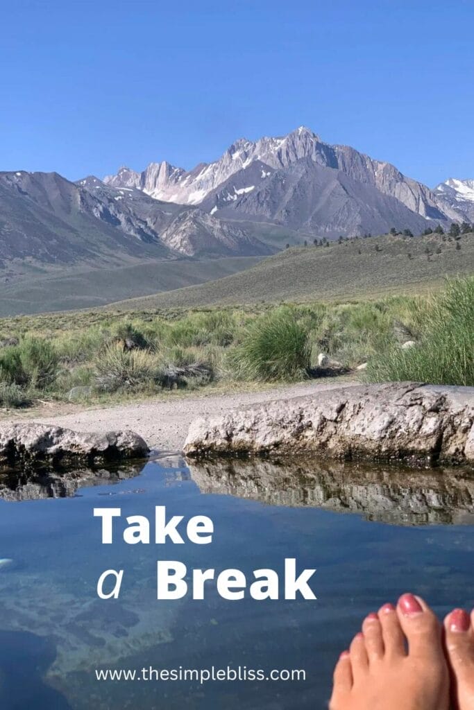 View from the Rock Tub Hot Springs pool with toes showing, Sierra mountains in the background, and clear blue sky.