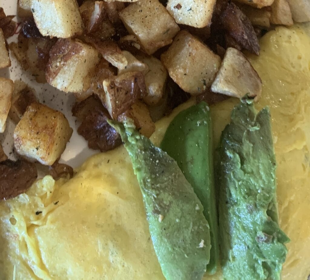 JUST Egg omelette served at Breakfast Republic with sliced avocados on top and a country hash potatoes on the side.