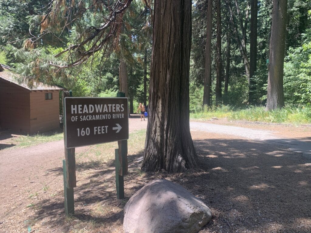 A wooden sign in the forest that reads "Headwaters of Sacramento River 160 Feet" with an arrow showing which direction to get to cold springs.