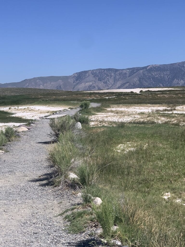 Picture of the walk from parking lot to the Hilltop Hot Springs Pool, which is located on that bare hill before the mountains.