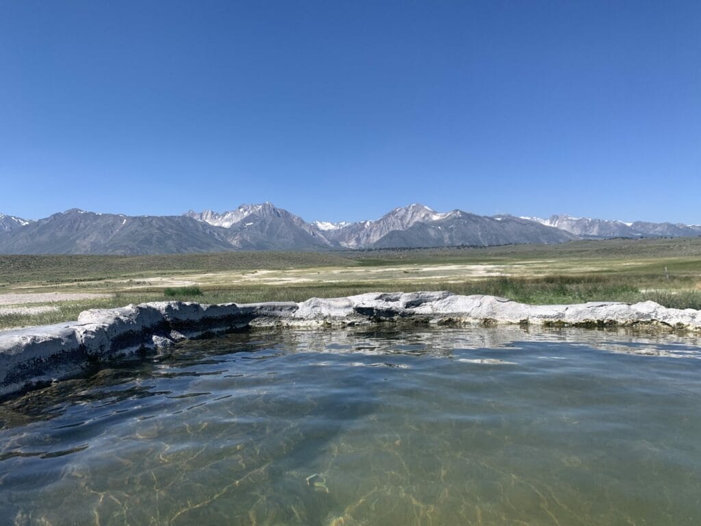 View from the Hilltop Hot Springs, a Mammoth Hot Springs, looking in a distance at snowcapped mountains is so tranquil to soak in.