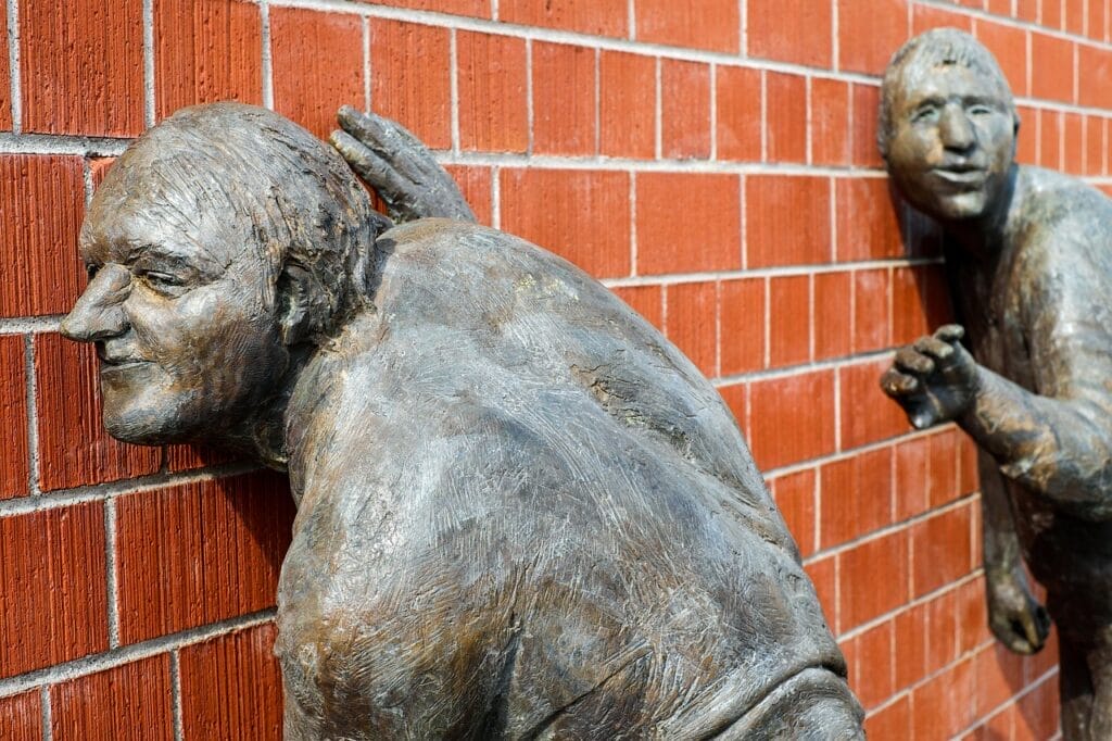 Bronze sculptures listening through the brick wall.