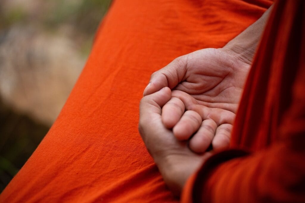 monk meditating image focusing on their hands.