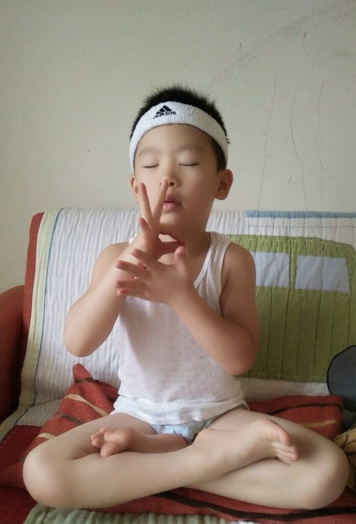 a young boy meditating with hands close to the face.