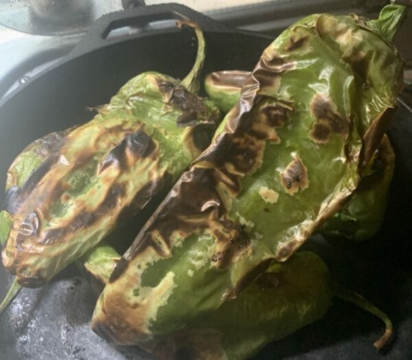 Hatch chiles perfectly roasted in a cast iron pan.