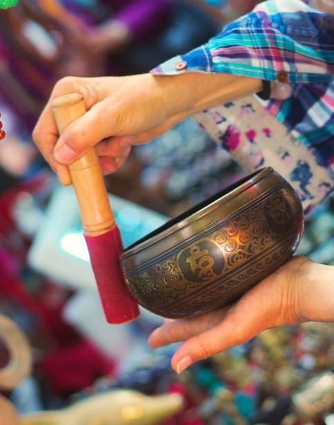 Woman using a Tibetan singing bowl with colorful background