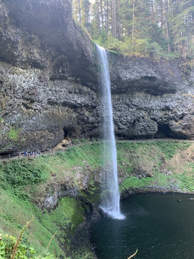 Silver Falls State Park's South Falls over a body of water with a walkway behind the waterfall.