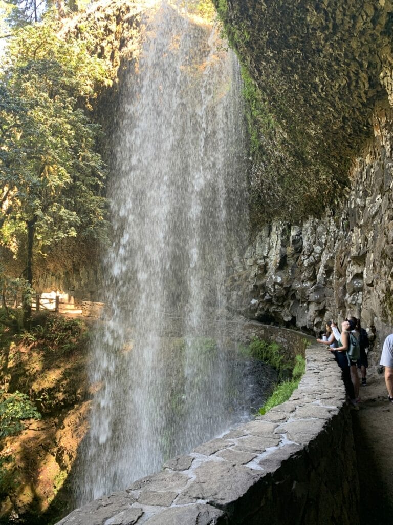 Walkway behind the waterfall with basalt rock walls.