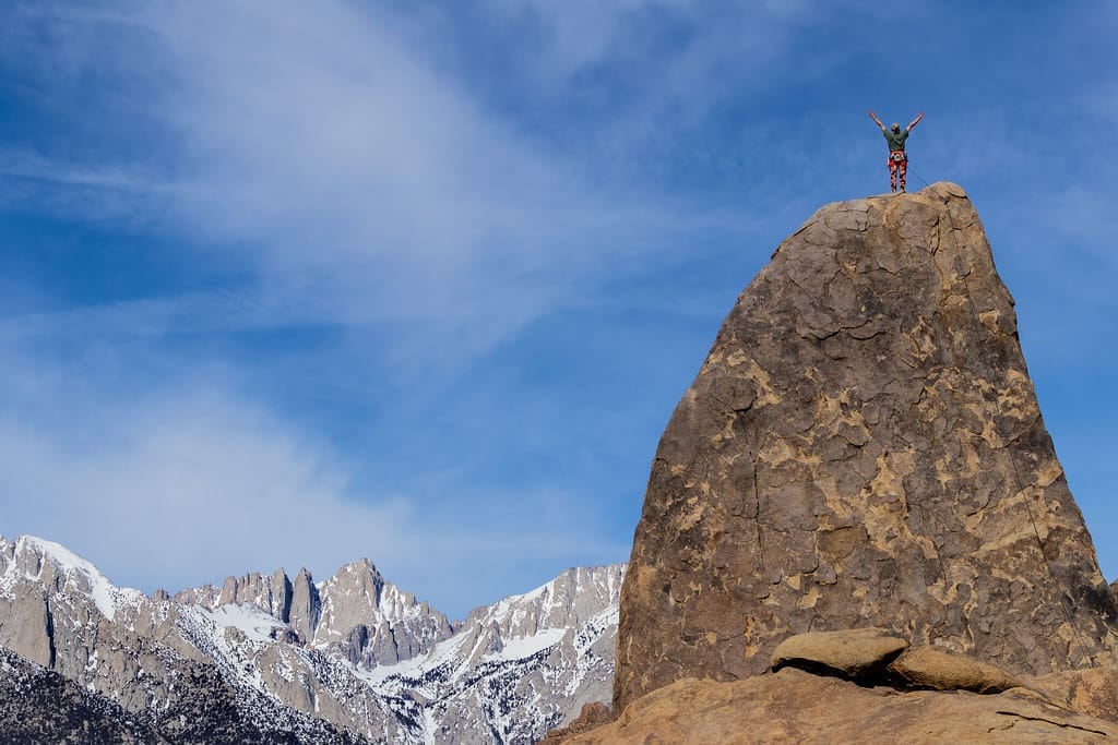 A person standing on top of a big boulder. Rock climbing is one of the popular sports in Alabama Hills.