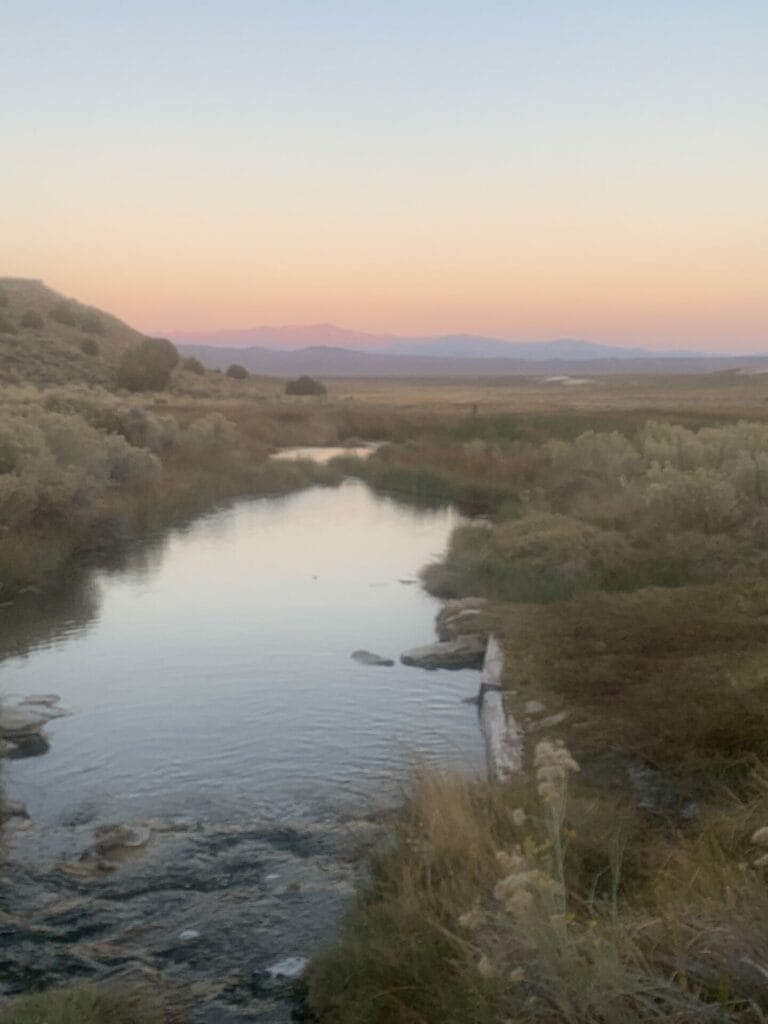 Picture of a little hot creek with grass banks during the sunset.