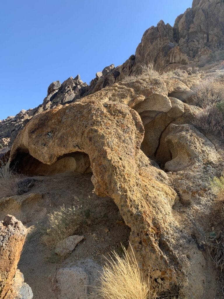 An interesting rock that is arched with carved in space, just sitting randomly amongst other rocks at Alabama Hills in California.