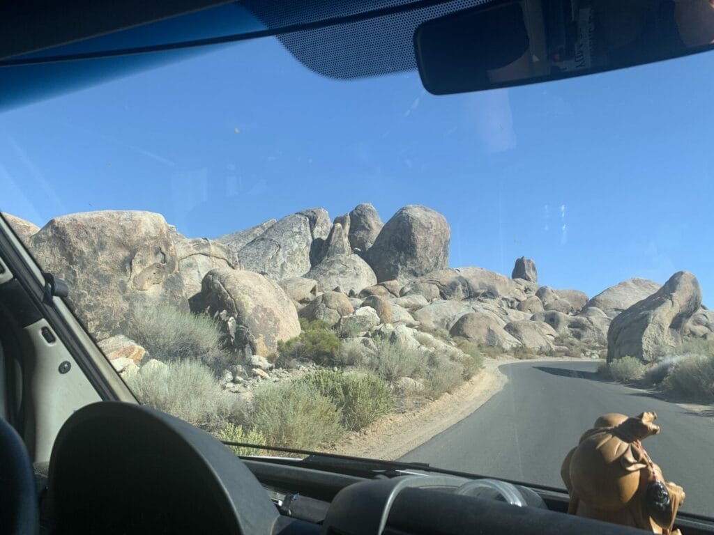 Scene from inside the car driving down the road with boulders on the sides of the road in Alabama Hills.