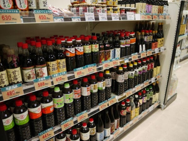 Picture of a shelf with bottles of fermented soy sauces and labels.