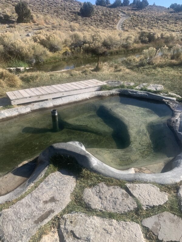 Siphon Hot Springs, aka Little Hot Creek is shown in the photo. A cemented tub of different levels with natural rocks.