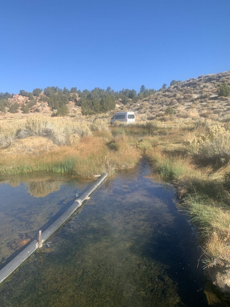 Pipe submerged in Little Hot Creek, leading the source water into Siphon Hot Springs. Our van is parked in the background.