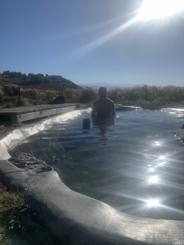 Siphon Hot Springs made from cement and natural rocks, water is glistening as the sun shines. Theron Hayes is enjoying the warm water.  