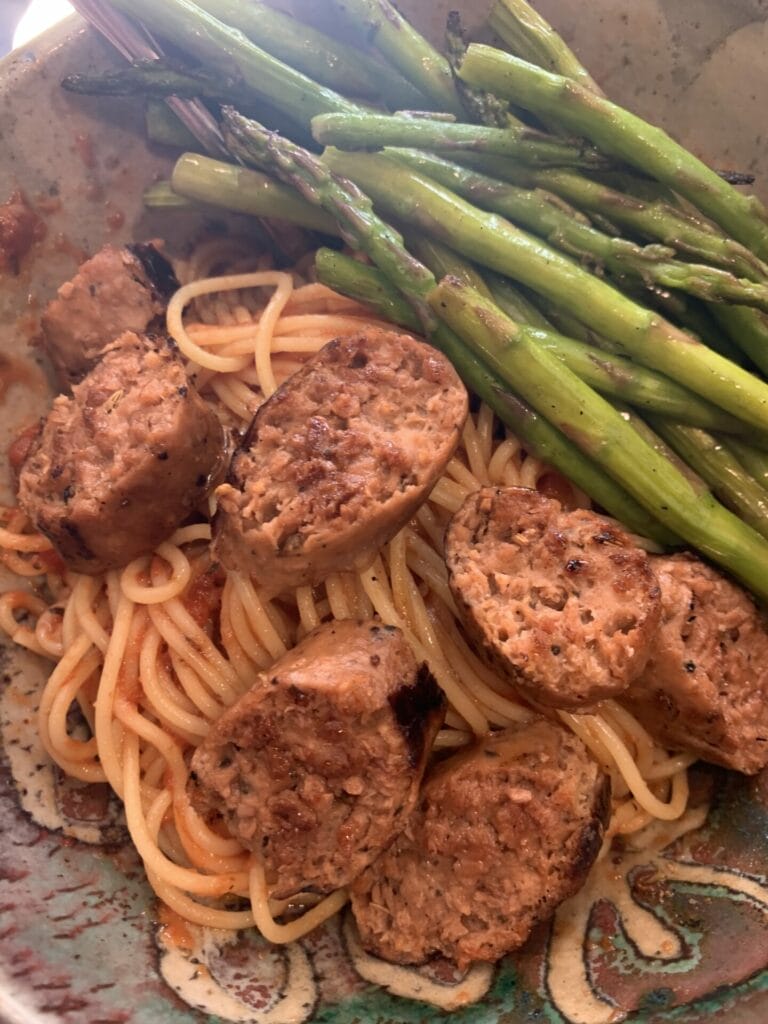 A bowl of spaghetti with sliced Gardein spicy Italian sausages and asparagus for my vegan sausage review.