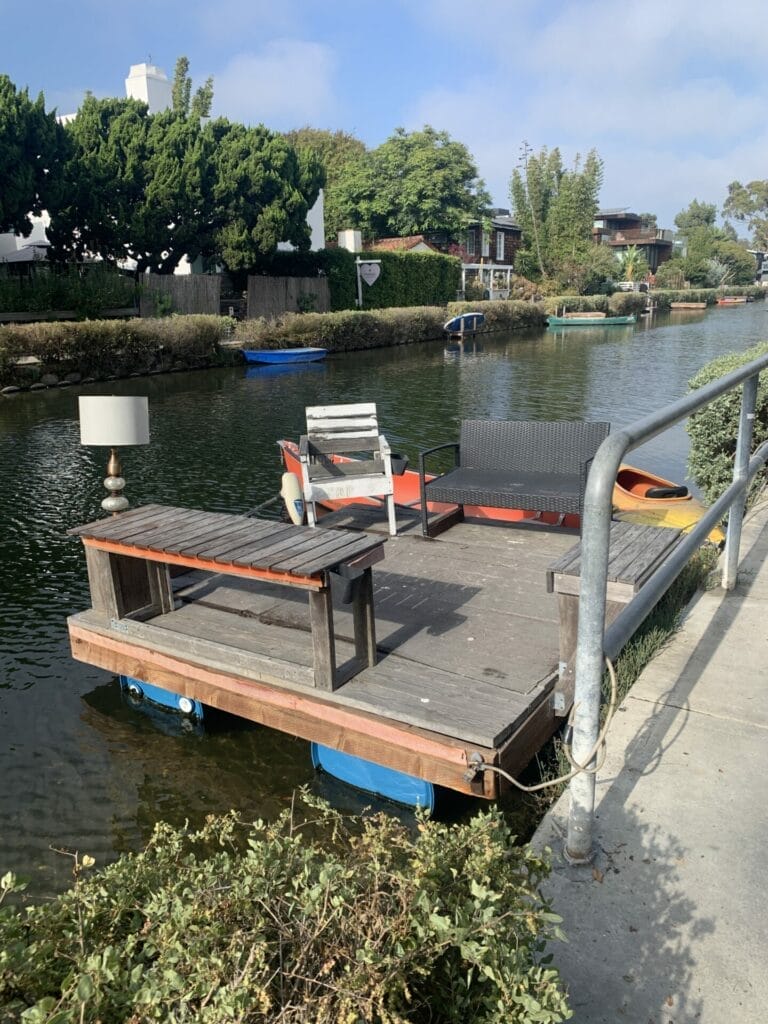 Private boat dock in Venice Beach Canals decorated with table, chair and table lamp.