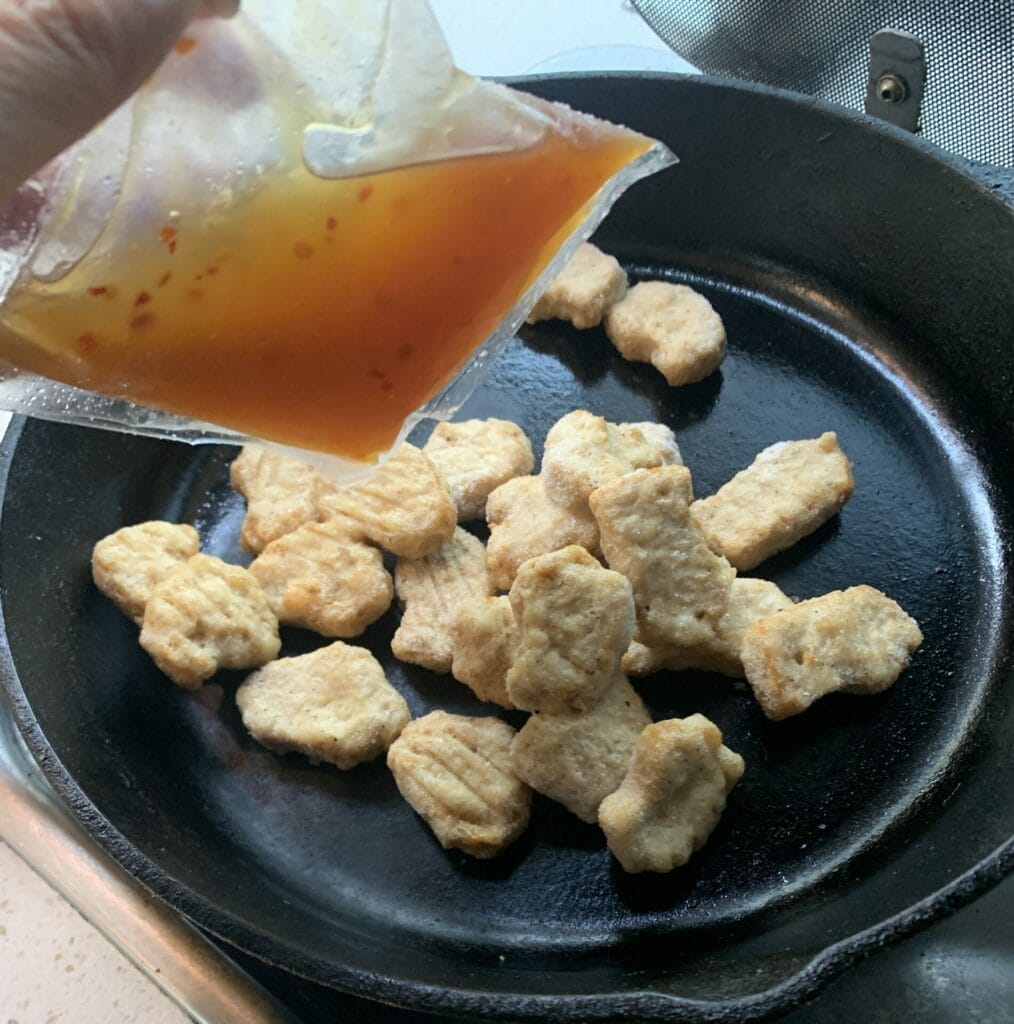 Frozen Chickenless Mandarin Orange Morsals in a pan with the packaged sauce, ready to be cooked up.