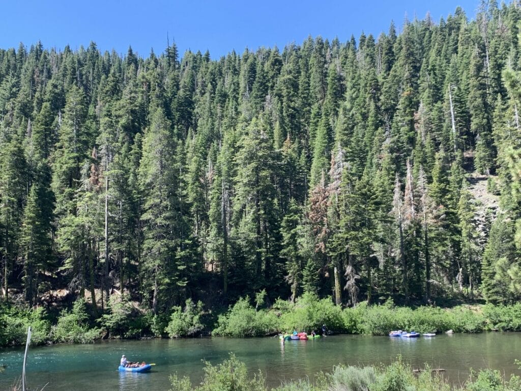 Truckee River with tubing kayaking and along the river there are people biking and walking.