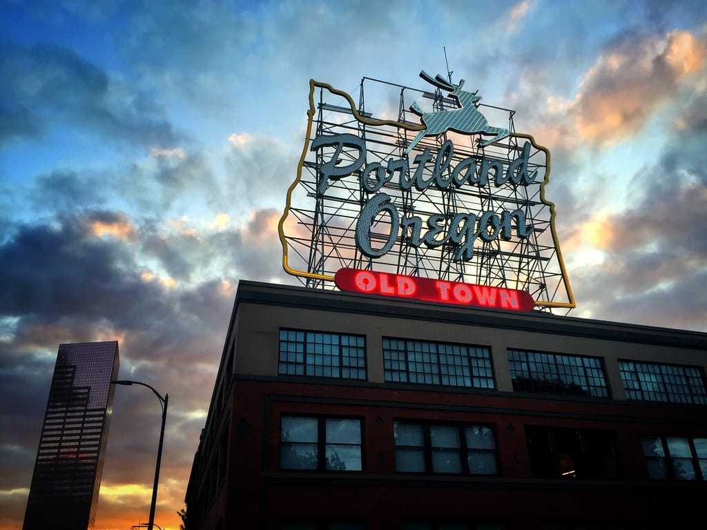 Portland, Oregon neon sign on top of an old brick building. Portland is one of the best vegan vanlife destinations in the US.